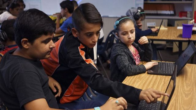 In this Tuesday, Oct. 4, 2016 photo, student Abdullah Arab, middle, 11, helps classmates Habeebullah Najme, left, 12, and Nada Alradi, right, 11, in a room filled with refugee children at Cajon Valley Middle School in El Cajon, Calif. According to the U.S. State Department, nearly 80 percent of the more than 11,000 Syrian arrivals over the past year were children. Many of those children are enrolling in public schools around the country, including Chicago; Austin, Texas; New Haven, Connecticut; and El Cajon, which received 76 new Syrian students the first week of school. (AP Photo/Christine Armario)
